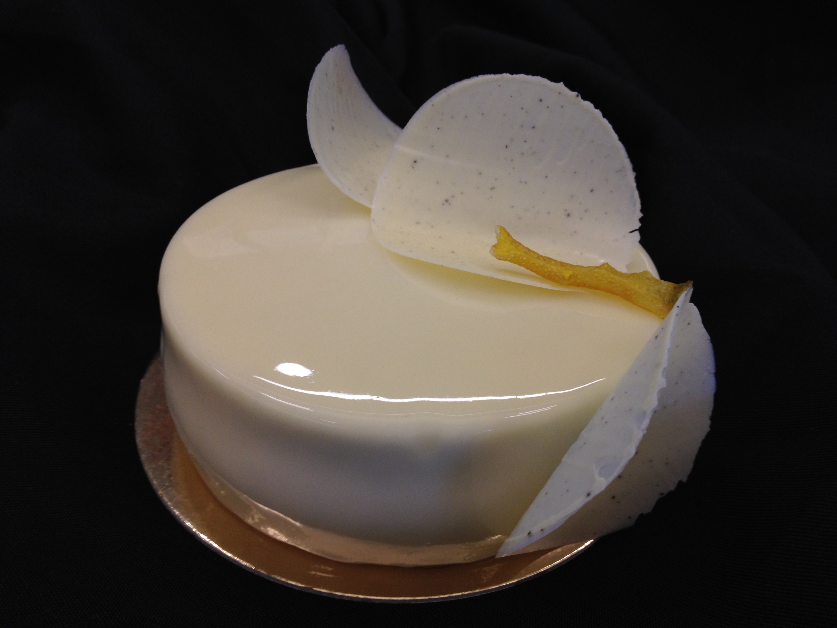 Yuzu and mandarin petit gâteau with a curved pale decoration