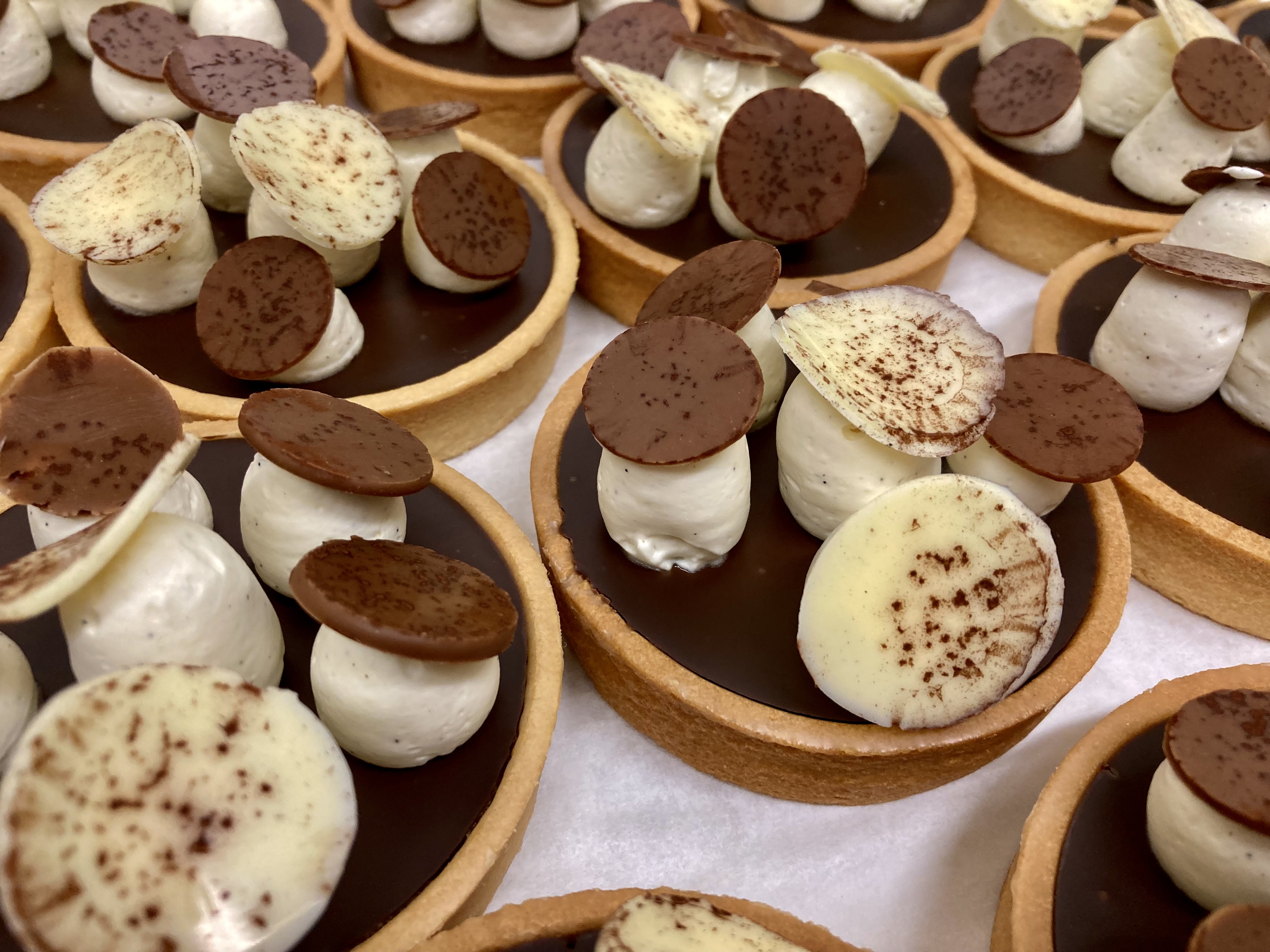 Dark chocolate and hazelnut tarts decorated with vanilla crema and chocolate bubbles resembling mushrooms