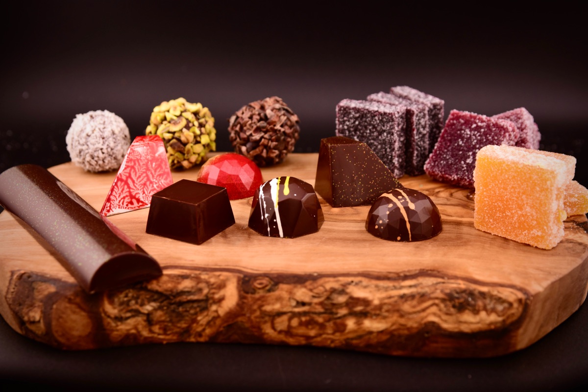 An assortment of Alpen bonbons, truffles, and fruit confections on a wooden board