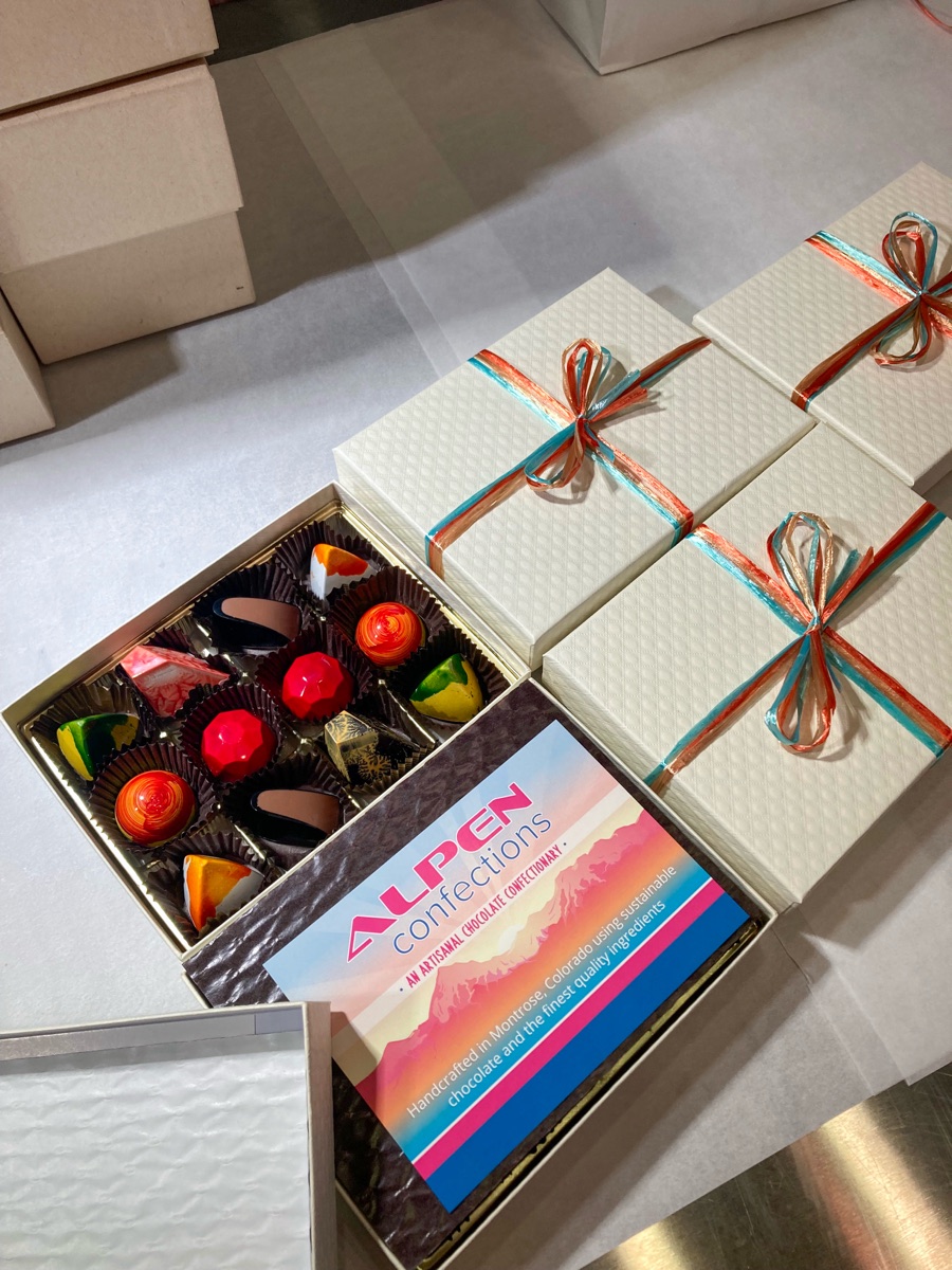 An open confection assortment beside ribboned gift boxes